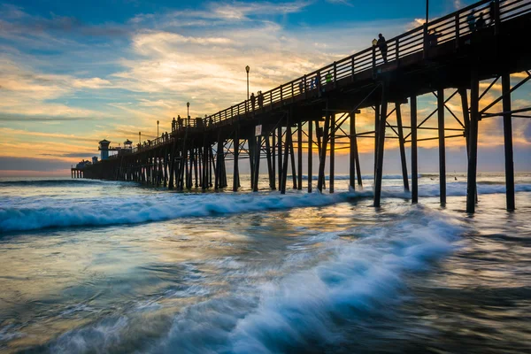 The pier and waves in the Pacific Ocean at sunset, in Oceanside, — Stock Photo, Image