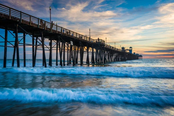 The pier and waves in the Pacific Ocean at sunset, in Oceanside, — Stock Photo, Image