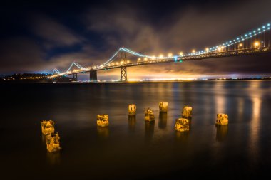 Pier pilings and the San Francisco - Oakland Bay Bridge at night clipart