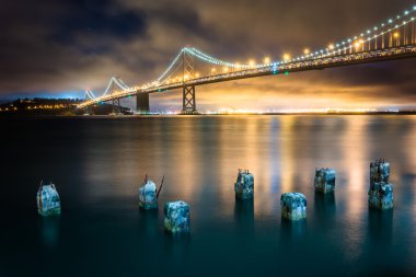 Pier pilings and the San Francisco - Oakland Bay Bridge at night clipart