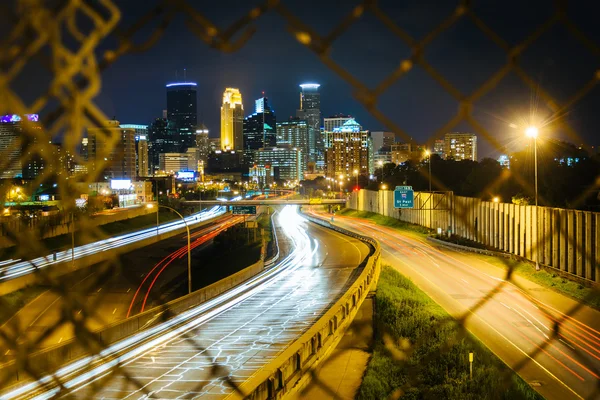 Chain link fence and view of I-35 and the skyline at night, seen — Stock Photo, Image