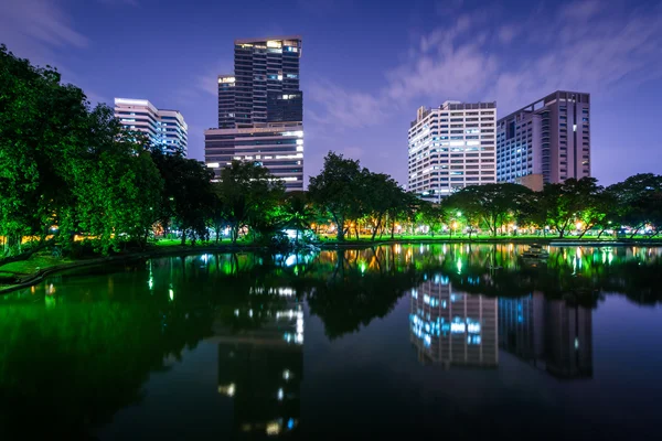 Lago y rascacielos por la noche, en Lumphini Park, en Bangkok, Tha — Foto de Stock