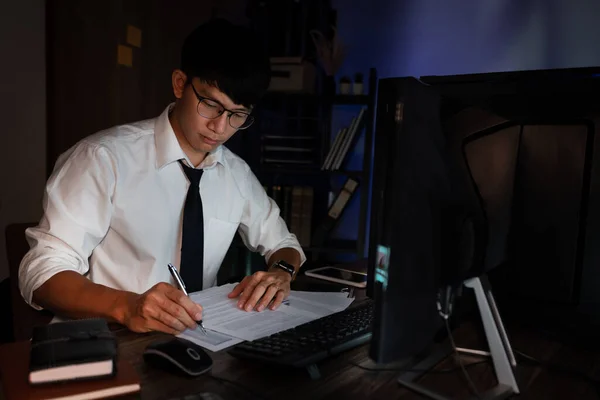 有吸引力的年轻亚洲商人集中工作到深夜 晚上在黑暗的现代办公室里的办公桌前出版 超负荷工作的概念 — 图库照片