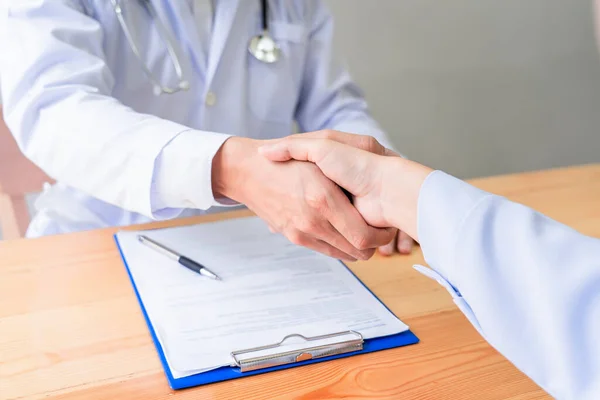 Medicine healthcare and trust concept, Asian doctor shaking hands with patient colleague after talking about medical examination results