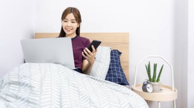 Evde, sosyal medyada akıllı telefon veya tabletle çalışan Asyalı kadın, evde kalıp karantina veya uzak çalışma ve yaratıcılık kavramı