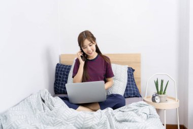 Evde, sosyal medyada akıllı telefon veya tabletle çalışan Asyalı kadın, evde kalıp karantina veya uzak çalışma ve yaratıcılık kavramı