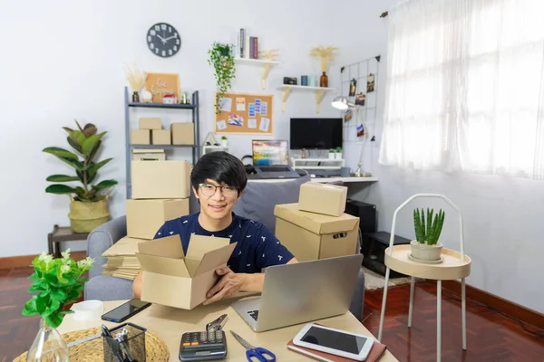 Asian man business owner or selling merchance online and prepare product packaging cardboard parcel box for send order shipment to client at home, shopping online, business owner, delivery concept