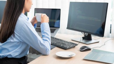 Ofisinde program veya uygulama geliştirmek için bilgisayarla kaynak kodunu yazan Asyalı kadın programcı