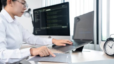 Genç Asyalı kadın programcı daktilo kodu masadaki bilgisayarla çalışıyor, siber uzay ve web geliştirme kavramını kodluyor.