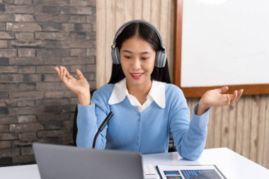 Eğitim konsepti. Genç zeki bayan öğretmen internet kameralarına bakıyor ve Coronavirus salgını sırasında bilgisayardan video konferans görüşmesiyle online ders veriyor..