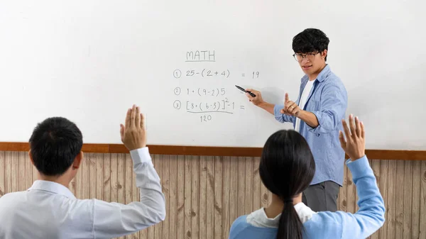 教育の概念コヴィッド 19流行前の教室でのハード数学の決定を説明する若いスマート男性教師 — ストック写真