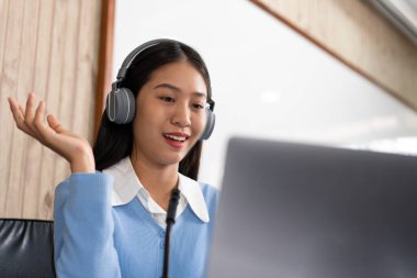 Eğitim konsepti. Genç zeki bayan öğretmen internet kameralarına bakıyor ve Coronavirus salgını sırasında bilgisayardan video konferans görüşmesiyle online ders veriyor..