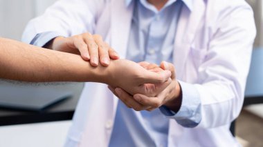 Tıbbi konsept. Erkek doktor, erkek hastaya bilek kemiğine bastırarak bilek tanısı koyar.