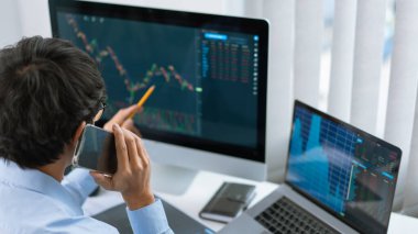 Finansal konsept. Bir erkek tüccar cep telefonuyla mevcut hisse senedinin eğilimi hakkında konuşuyor.
