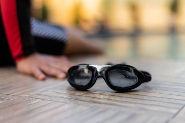 Spor ve eğlence konsepti siyah yüzme gözlükleri yüzme havuzuna yerleştirilmiş mayo giymiş bir çocukla.