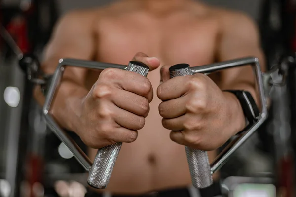 トレーニングジムのコンセプト筋肉質の男性ティーンエイジャー彼の胸を開発するために前進を繰り返すジム機器を使用して — ストック写真