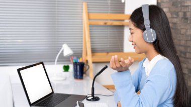 Eğitim konsepti. Genç zeki bayan öğretmen internet kameralarına bakıyor ve Coronavirus salgını sırasında bilgisayardan video konferans görüşmesiyle online ders veriyor..