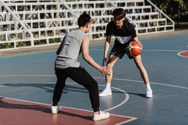 Spor ve eğlence konsepti. İki erkek basketbolcu, spor sahasında birlikte basketbol oynamaktan zevk alıyor..