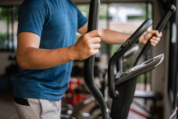 トレーニングジムのコンセプト彼の健康的なルーチンとしてジムでサイクリングマシンで心臓トレーニングを行う男性ティーネージャー — ストック写真