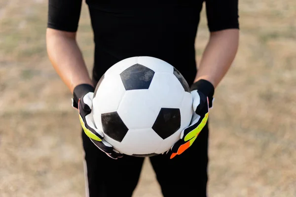 体育和娱乐的概念 一个身穿黑色服装 头戴彩色手套 手持足球的男性青少年守门员 — 图库照片