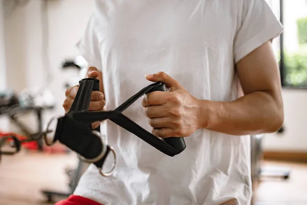 トレーニングジムのコンセプトマシンに対して彼の両方の筋肉の腕を引くジム機器を使用して男性ティーンエイジャー — ストック写真