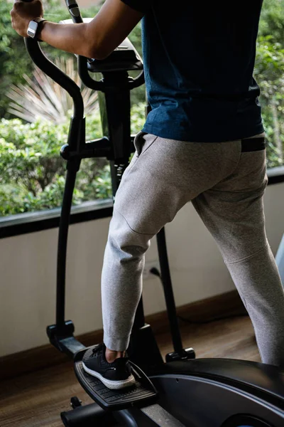 トレーニングジムのコンセプト彼の健康的なルーチンとしてジムでサイクリングマシンで心臓トレーニングを行う男性ティーネージャー — ストック写真