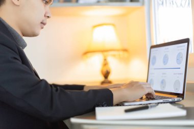 İş ortakları, genç bir işadamının yıllık satış özetini düzenleyen bir dizüstü bilgisayar kullanmasını kavramsallaştırıyor.