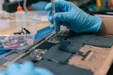 Telefon tamir konsepti. Genç bir elektrik teknisyeni, elektronik bir cihazın parçalarını tornavida kullanarak takıyor..