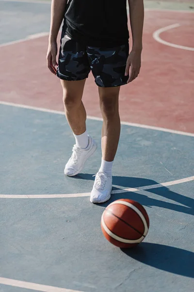 体育和娱乐的概念一个身穿黑色服装和白色鞋子的年轻运动员站在篮球场旁边 — 图库照片