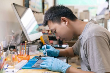 Telefon tamir konsepti. Genç bir elektrik teknisyeni, elektronik bir cihazın parçalarını tornavida kullanarak takıyor..