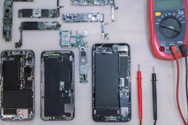 Telefon tamir konsepti. Parçalara ayrılan çeşitli elektronik cihazlar. Kapaklar, devre kartları, vücutlar gibi..