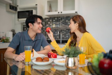 Neşeli Asyalı ortaklar, besleyici bir sabah yemeğiyle güne başlıyorlar. Meyve ve içeceklerle birbirlerine sevgiyle bağlılar..