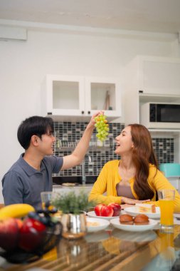 Yetişkin Asyalı çift lezzetli, sağlıklı kahvaltıdan, taze meyveli pastalardan, parlak, modern ev yapımı mutfaklardan ve neşeli anlardan hoşlanır.