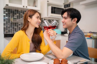 Neşeli Asyalı ortaklar evlerinde romantik şarap tostlarını paylaşırlar. Derin bir sevgi ve bağın kutlaması. Yetişkinler birlikte vakit geçirmekten zevk alırlar.