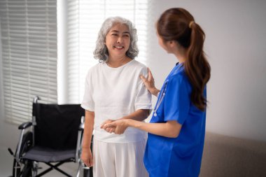 Asyalı hemşire, sağlık ve profesyonel bakımı sağlayan yaşlı bir kadın için şefkatli bir ev bakımı sunuyor.