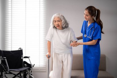 Profesyonel Asyalı bakıcı, yaşlı bir hastaya evde fiziksel rehabilitasyon eğitimi almasında yardımcı oluyor