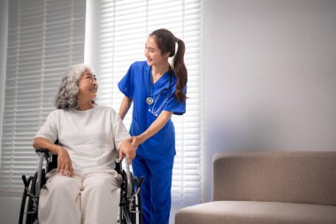 Merhametli Asyalı hemşire yaşlı kadın tekerlekli sandalye hastasına yardım ediyor. Dostça destek sağlama tıbbi yardım kişisel konfor ev sağlığı ortamı.