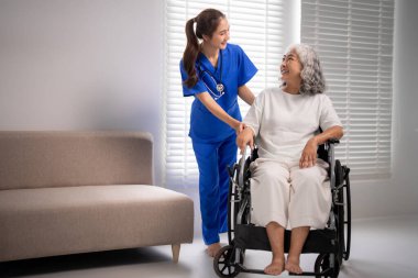 Nazik Asyalı hemşire tekerlekli sandalyedeki kıdemli hastayı destekliyor profesyonel bakıcı sağlık mutluluğunu desteklemek için özenli empatik yardım sağlıyor