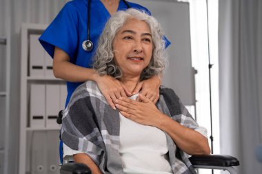 Profesyonel Asyalı hemşire yaşlı bir Asyalı kadına şefkat gösteriyor. Hasta, ev içi sağlık hizmeti sunucusundan konfor ve duygusal destek görüyor.