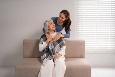 Genç Asyalı yetişkin kadın yaşlı dişiye şefkatli bir rahatlık sağlıyor. Duygusal bağ, sevgi desteği, aile refahı, yuva kurmak. Yaşlıveliler için bakım.