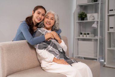 Asyalı kadın nesiller, gülümsemeyle sevgi bağı kuruyor sıcak kucak ev oturma odası, nesiller arası sevgi aile desteği kuruyor.