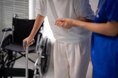 Sağlık personeli rehberi yaşlı kişi tekerlekli sandalye desteğiyle yürüyor ev sağlığı kliniği hasta hareketliliği iyileşme sürecine odaklanıyor