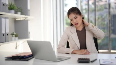Yetişkin Asyalı kadın profesyonel tecrübesi. Boyun ağrısı şikayeti. Dizüstü bilgisayar üzerinde çalışırken modern ofis ortamında.