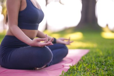 Yoga minderinde meditasyon yapan bir kadının yakın görüntüsü. Doğal ortamlardaki dikkatli uygulamalarla iç huzurunu ve dengesini buluyor..