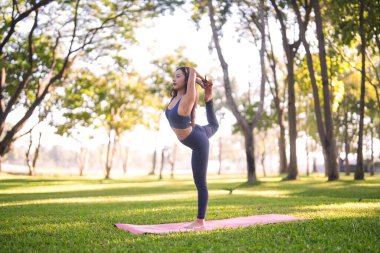 Yetişkin Asyalı kadın dışarıda yoga poziyonu veriyor. Bu huzurlu görüntü, barışın vücut kontrolünü ve zihinsel refahı temsil ediyor. Mükemmel sağlık motivasyonu.