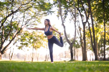 Formda bir Asyalı yetişkin kadın, huzurlu doğal park ortamında barışçıl fitness ortamında zorlu bir yoga dengesi kuruyor.