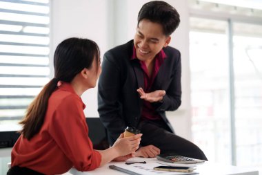 Asyalı meslektaşlar parlak, modern bir ofiste iş tartışması sırasında neşeli bir anı paylaşıyorlar. Pozitif takım çalışması yeniliği teşvik eder