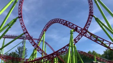Roller coaster in amusement park, tourists riding roller-coaster at summer