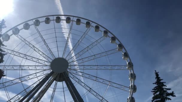 Колесо фріса в парку розваг обертається навколо ясного блакитного неба. — стокове відео