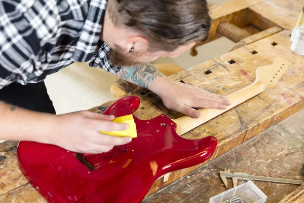 Artesano lijando un cuello de guitarra en madera en el taller —  Fotos de Stock